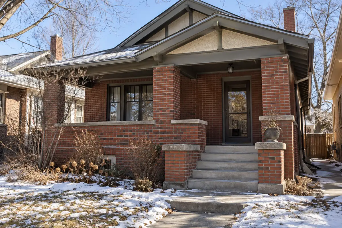 Brick bungalow with a covered porch and light snow on the lawn, storm shelter mold in Oklahoma City, OK